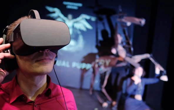 Mann mit Virtual Reality Brille bei der Vorszel eines analogen Figurentheaters