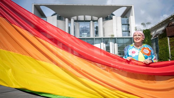 Claudia Roth hält die Regenbogenflagge vor dem Bundeskanzleramt hoch.