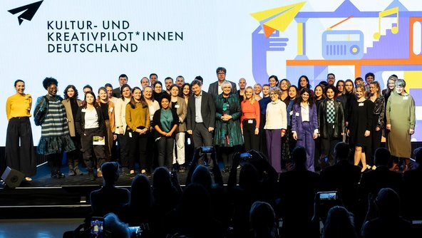 Gruppenfoto der Gewinnerinnen und Gewinner mit Kulturstaatsministerin Roth, Bundeswirtschaftsminister Habeck und dem Ansprechpartner der Bundesregierung für die Kultur- und Kreativwirtschaft Kellner