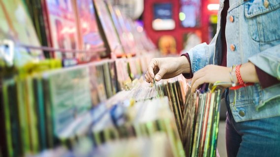 Eine Frau stöbert durch Schallplatten in einem Schallplattenfachgeschäft.