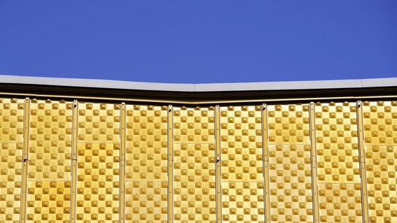 Blauer Himmel über der gelben Fassade der Philharmonie in Berlin