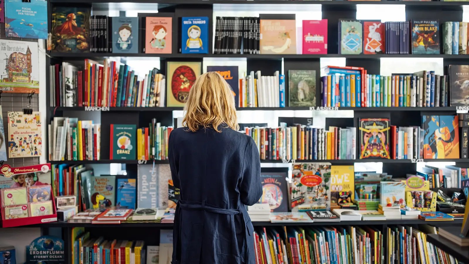 Frau in Buchhandlung vor Bücherwand